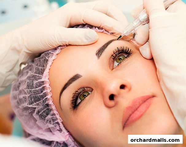 A close-up of a woman receiving permanent makeup on her eyebrows.