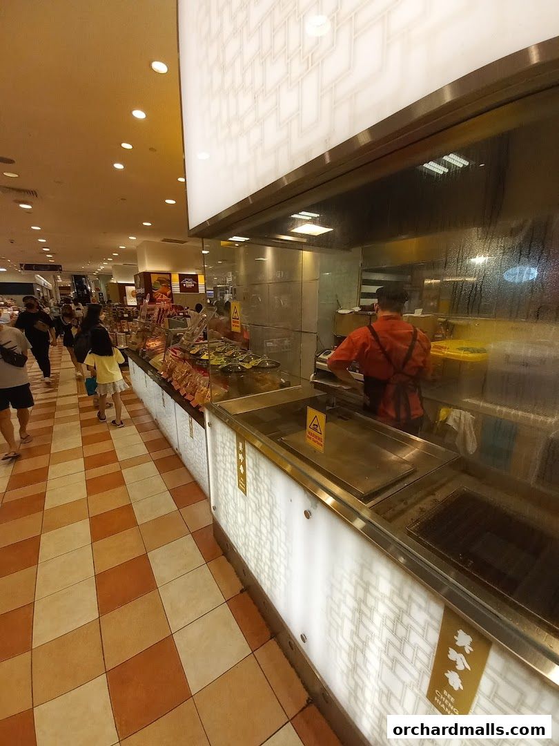A food stall with a chef preparing food behind a counter in a busy mall.