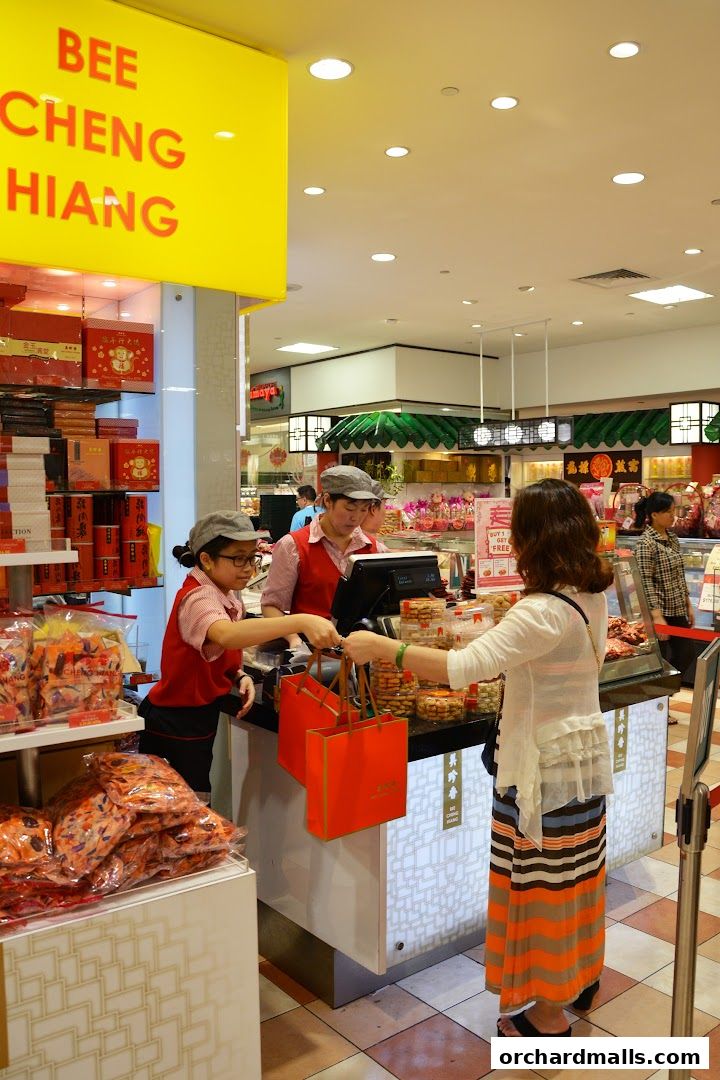 Customers are being served at the Bee Cheng Hiang counter with gift bags.