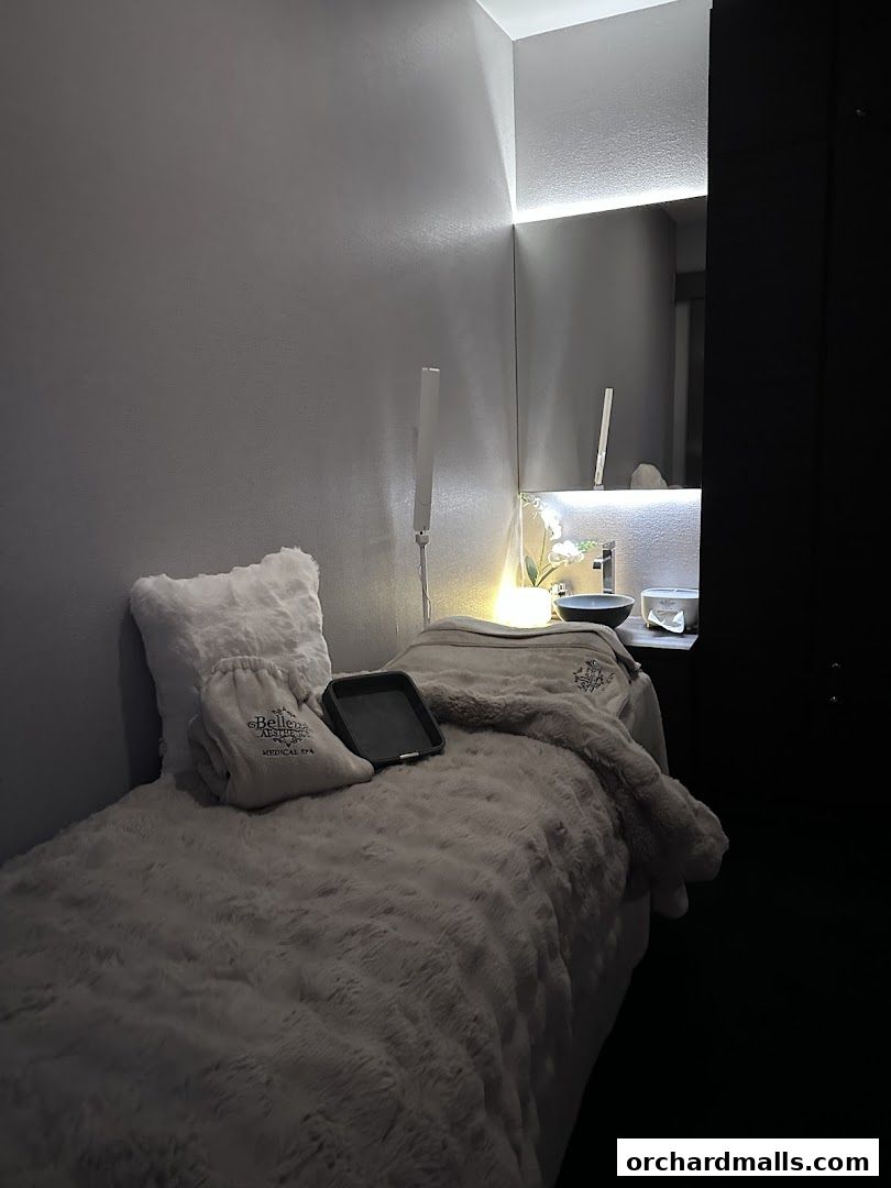 A treatment bed with plush blankets and pillows in a dimly lit spa room.