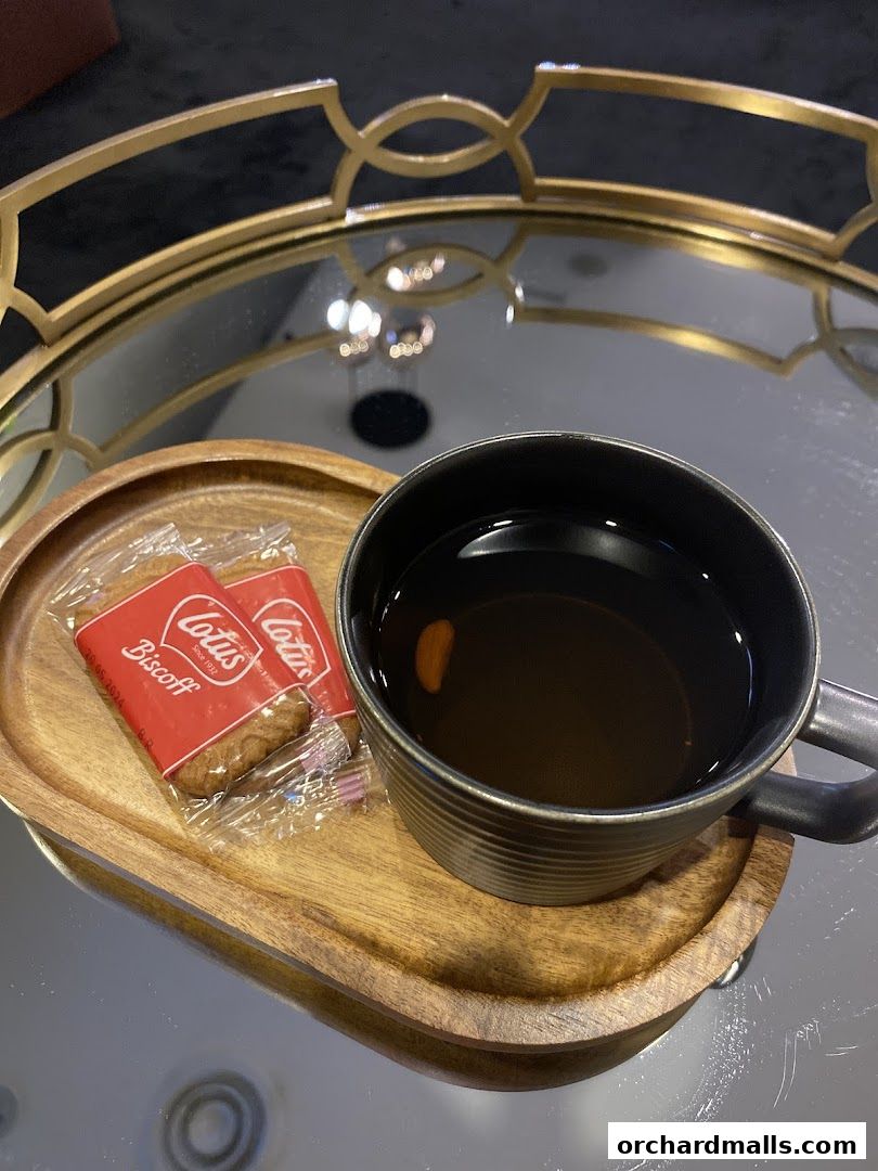 A cup of tea and two Biscoff cookies on a wooden tray.