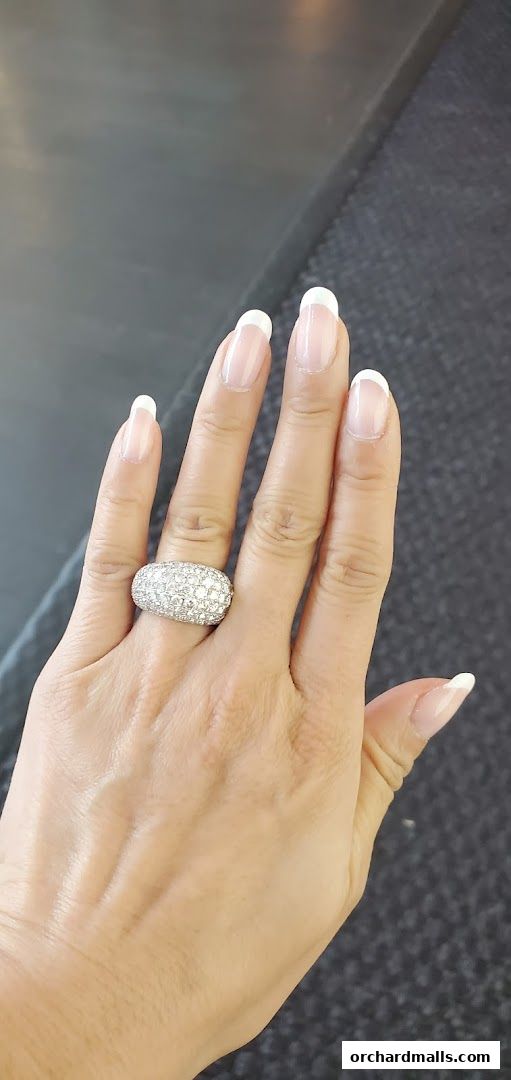 A hand with perfectly manicured French tip nails and a sparkling diamond ring.