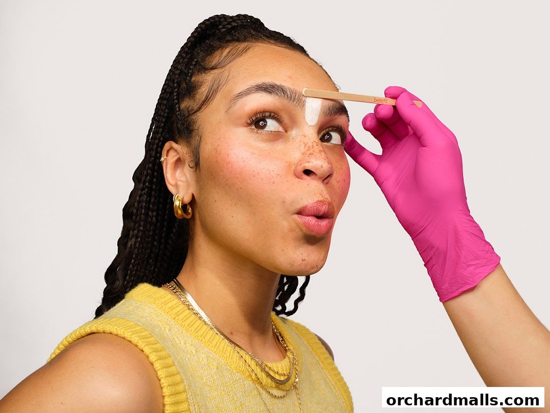 A person's eyebrow is being shaped with a spatula and white product.