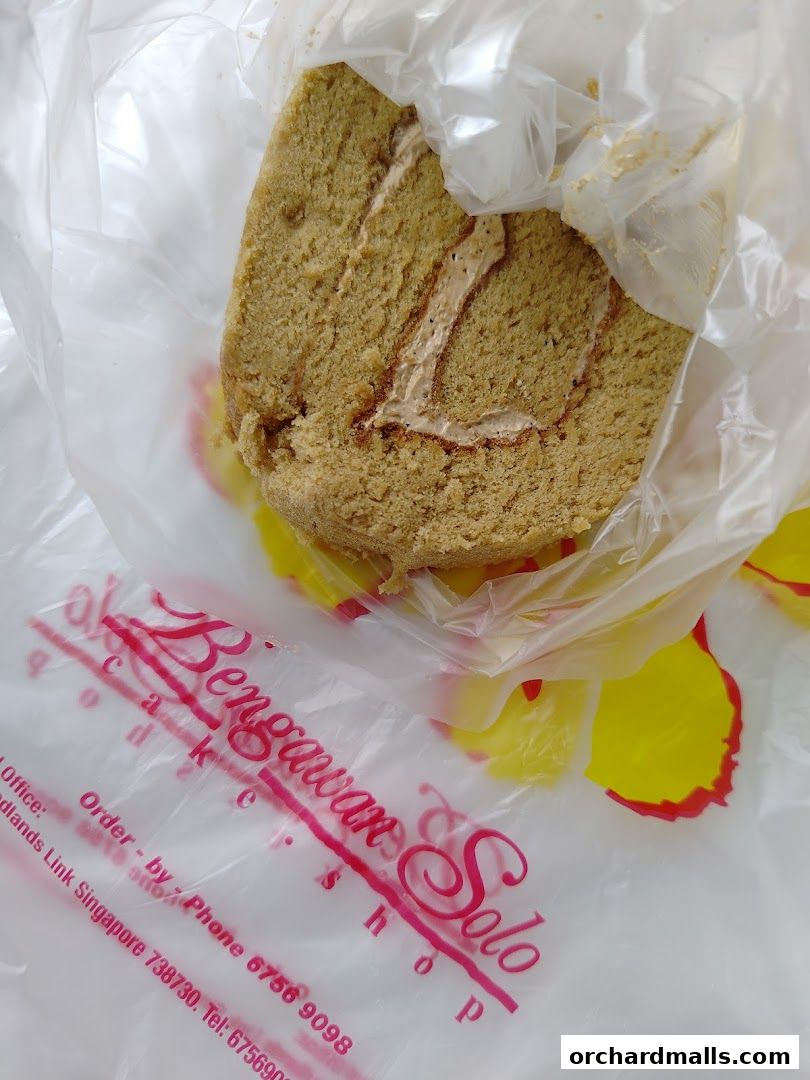 A slice of Swiss roll cake in plastic packaging with the shop's logo visible.