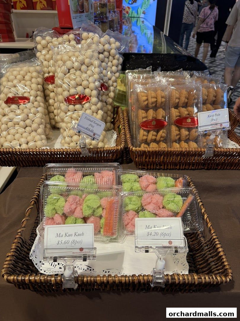 Assortment of packaged snacks and traditional kueh displayed in woven baskets.