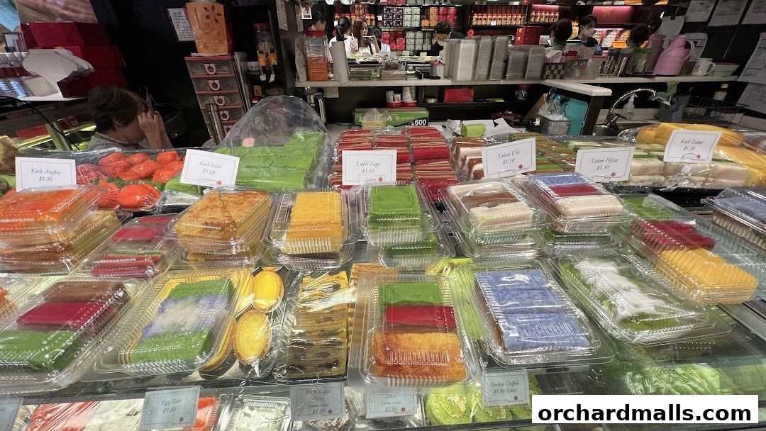 A display of colorful, layered cakes and pastries in clear plastic packaging.