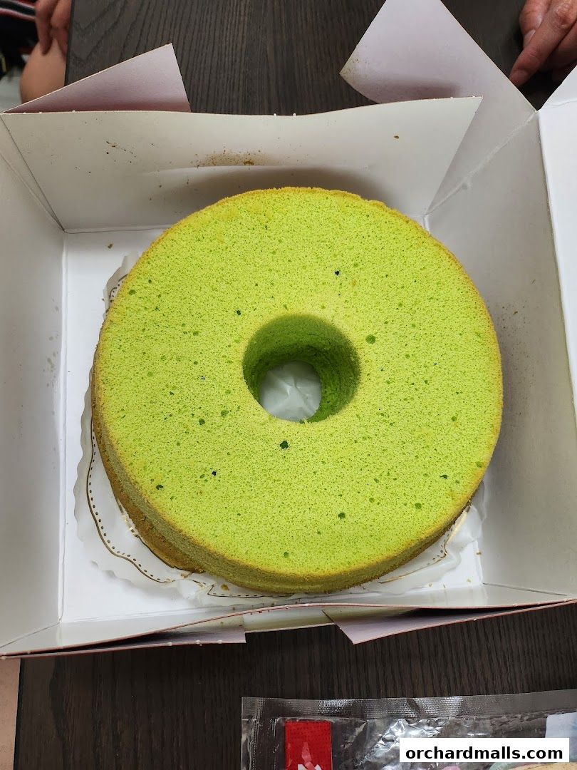 A bright green chiffon cake in a white box, ready to be enjoyed.