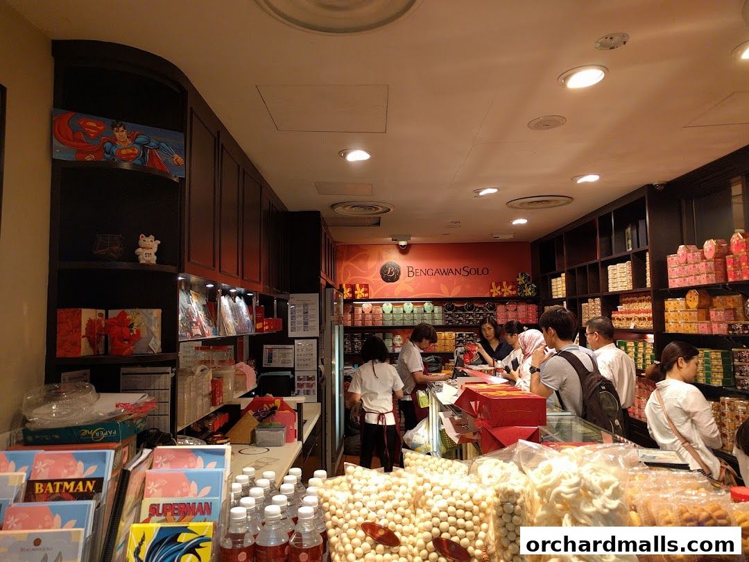 Interior of a shop with customers and staff, displaying various food products and gift boxes.