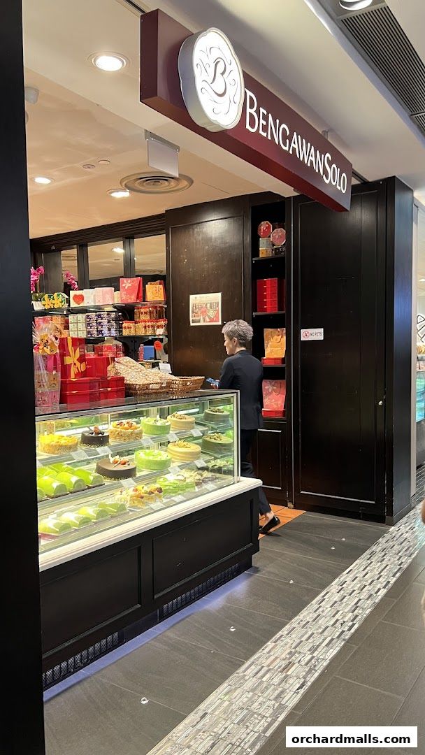 A display of cakes and pastries at Bengawan Solo, with a staff member attending.