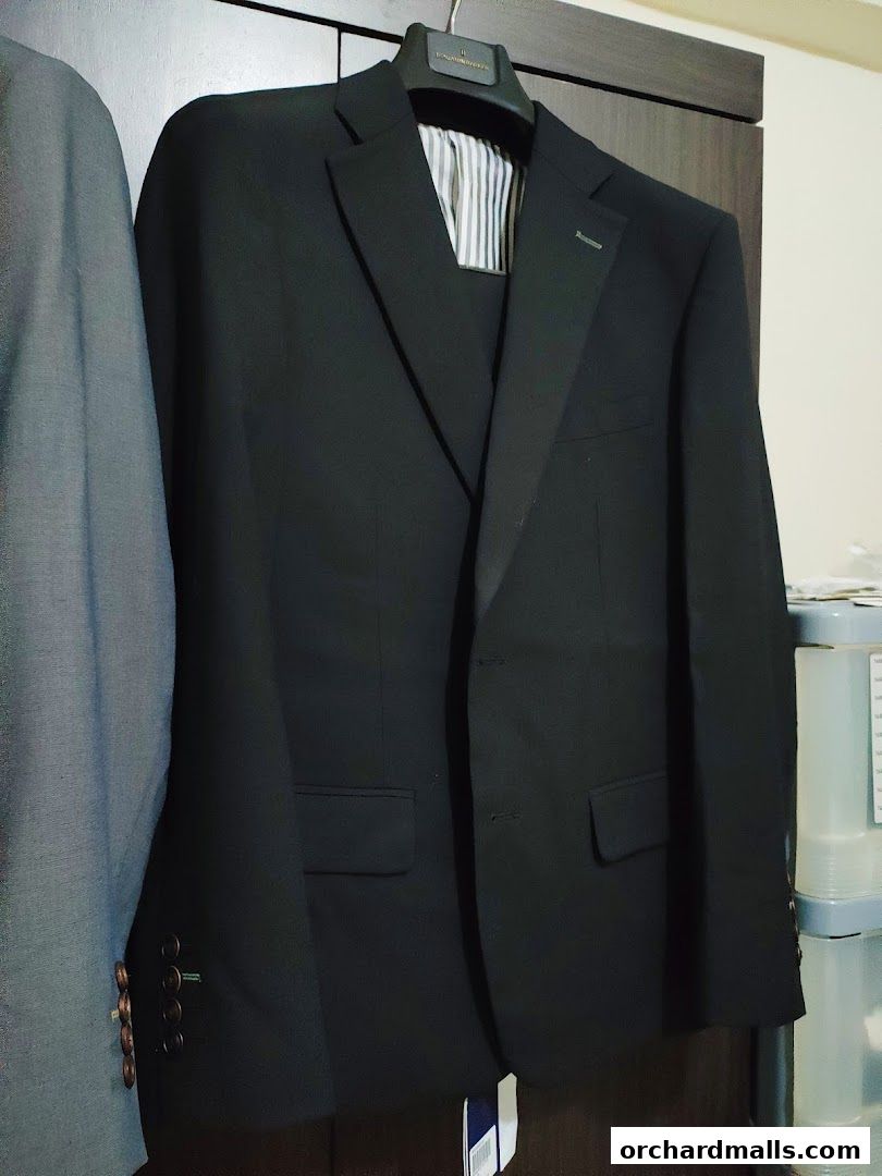 A black suit jacket and a grey suit jacket hanging on a rack.