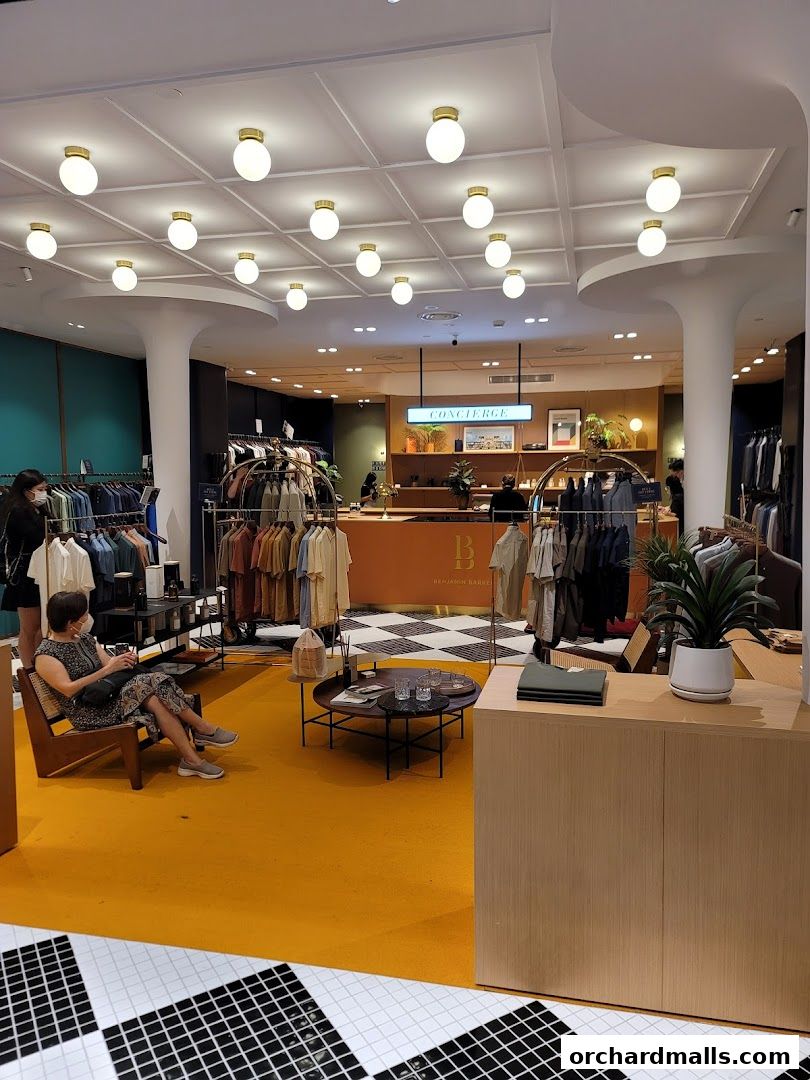 Interior of a stylish clothing store with apparel displayed on racks and a concierge desk.