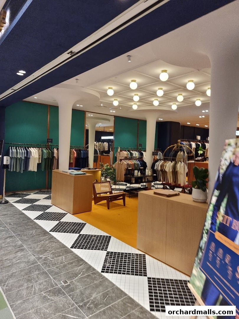 Interior view of a stylish clothing store with apparel displayed on racks and a seating area.