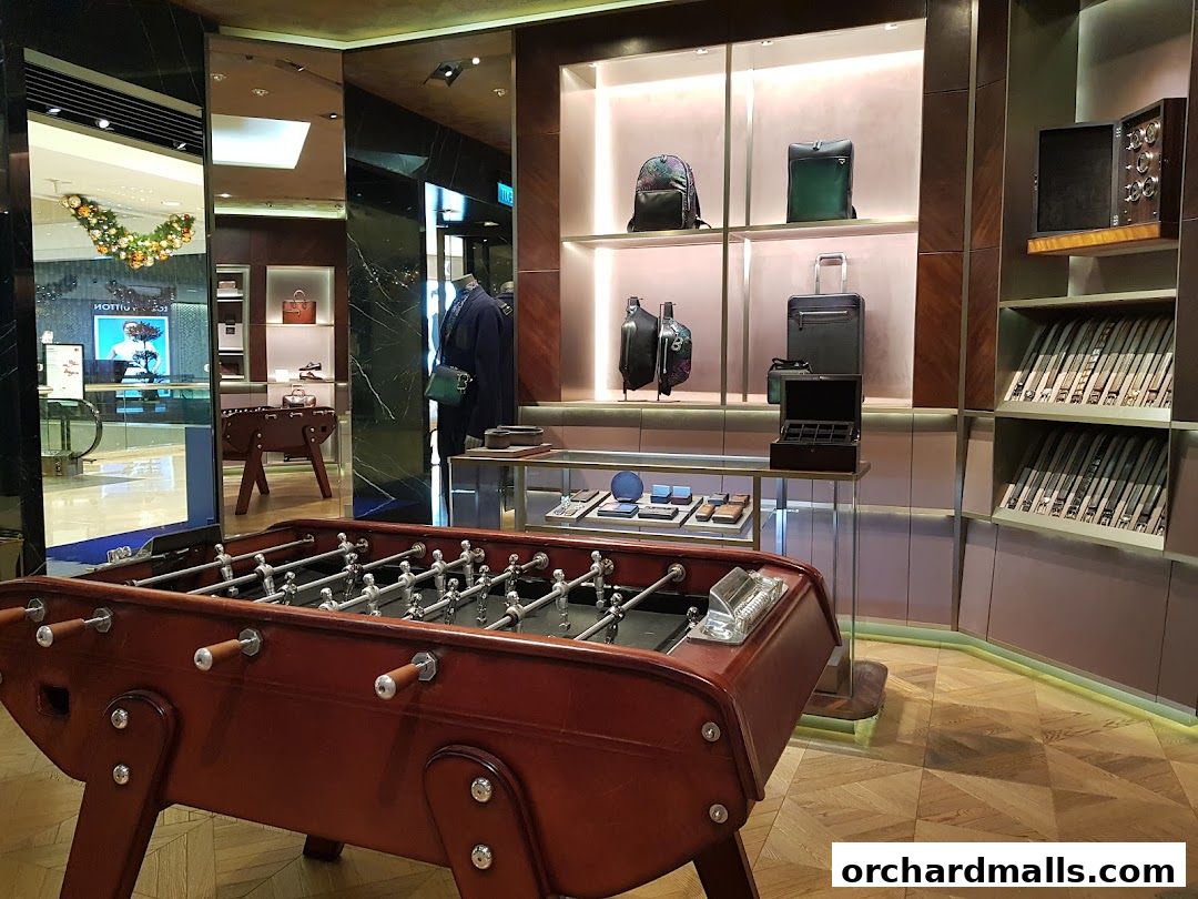 Interior of a luxury store featuring a foosball table and display shelves with bags and accessories.
