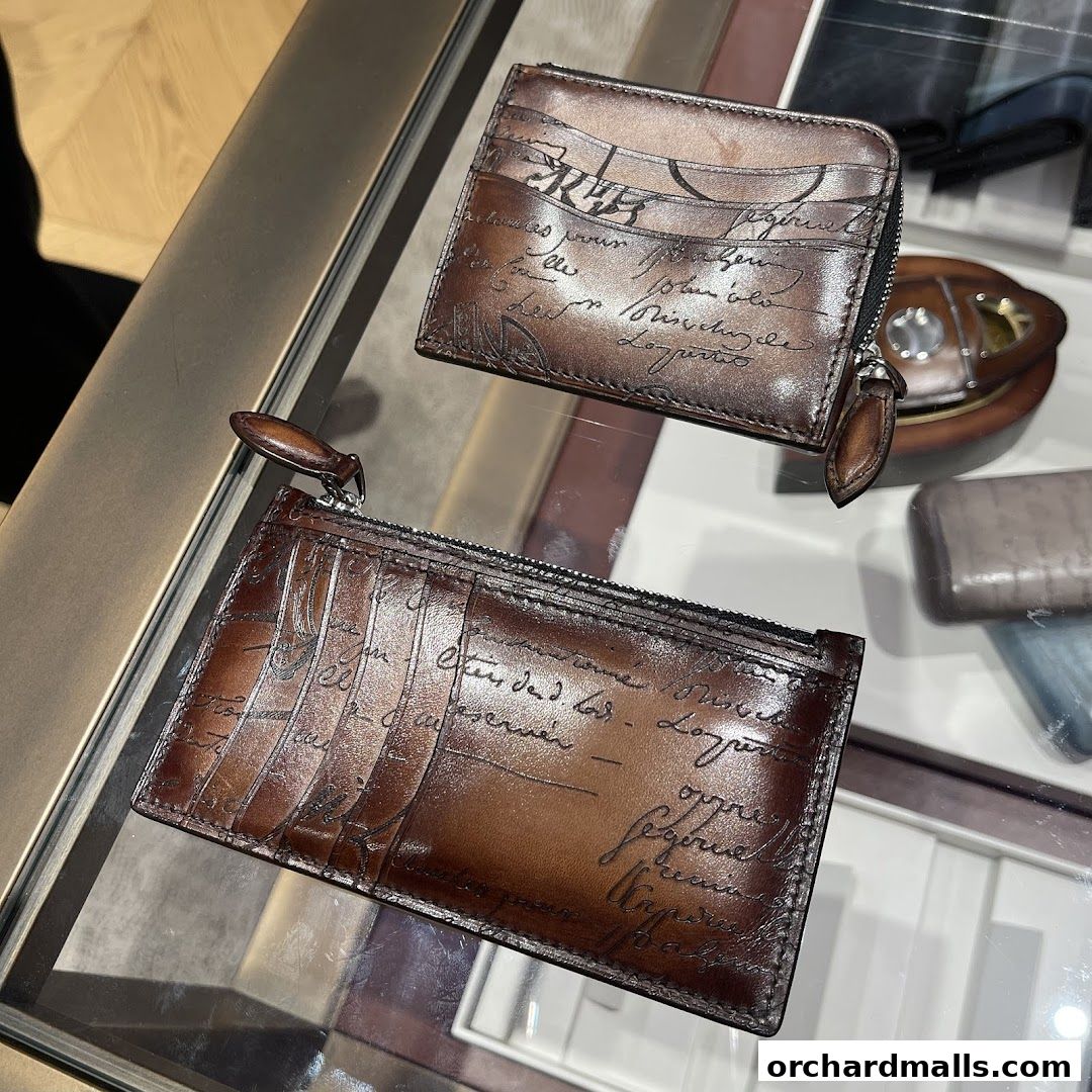 Close-up of two brown leather wallets with handwritten script designs.