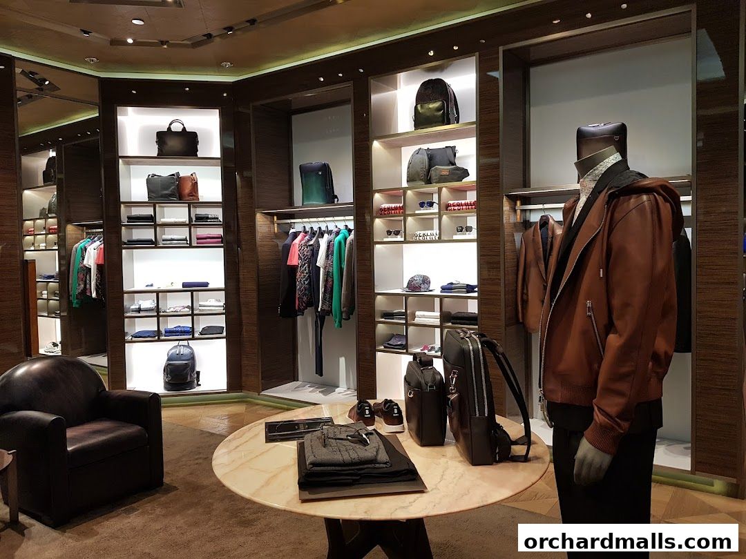 Interior of a luxury fashion store displaying clothing, bags, and accessories on shelves and mannequins.