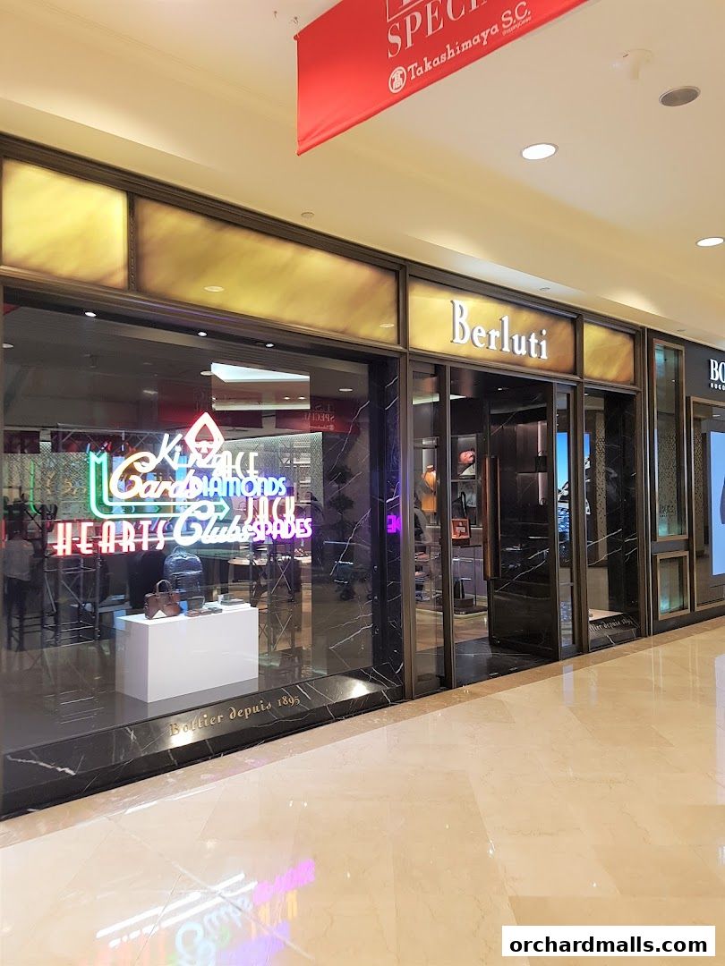 The exterior of the Berluti luxury fashion store with a display window.