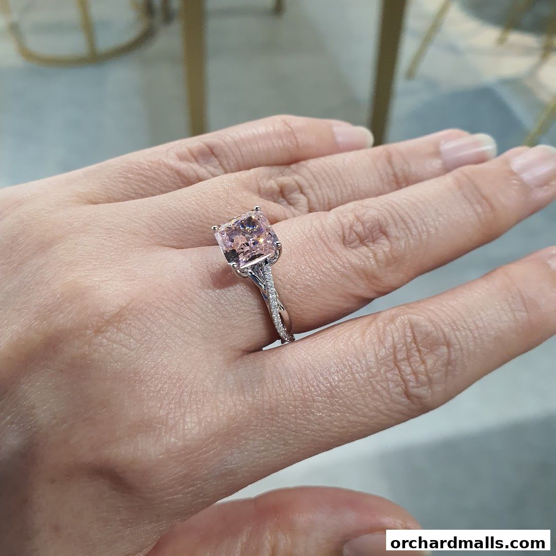 A hand wearing a stunning pink cushion-cut diamond ring with a twisted band.