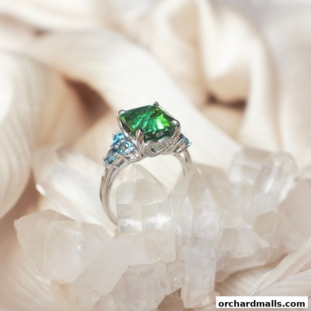 A stunning emerald and aquamarine ring rests on clear quartz crystals.