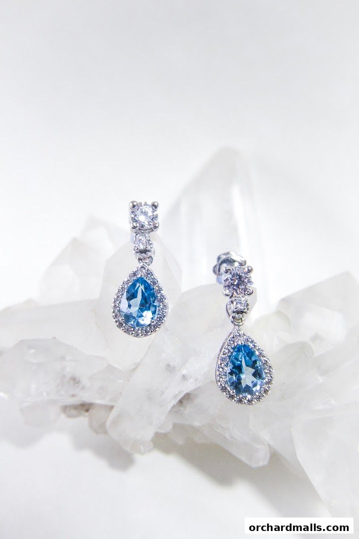 Elegant blue gemstone and diamond drop earrings displayed on clear crystals.