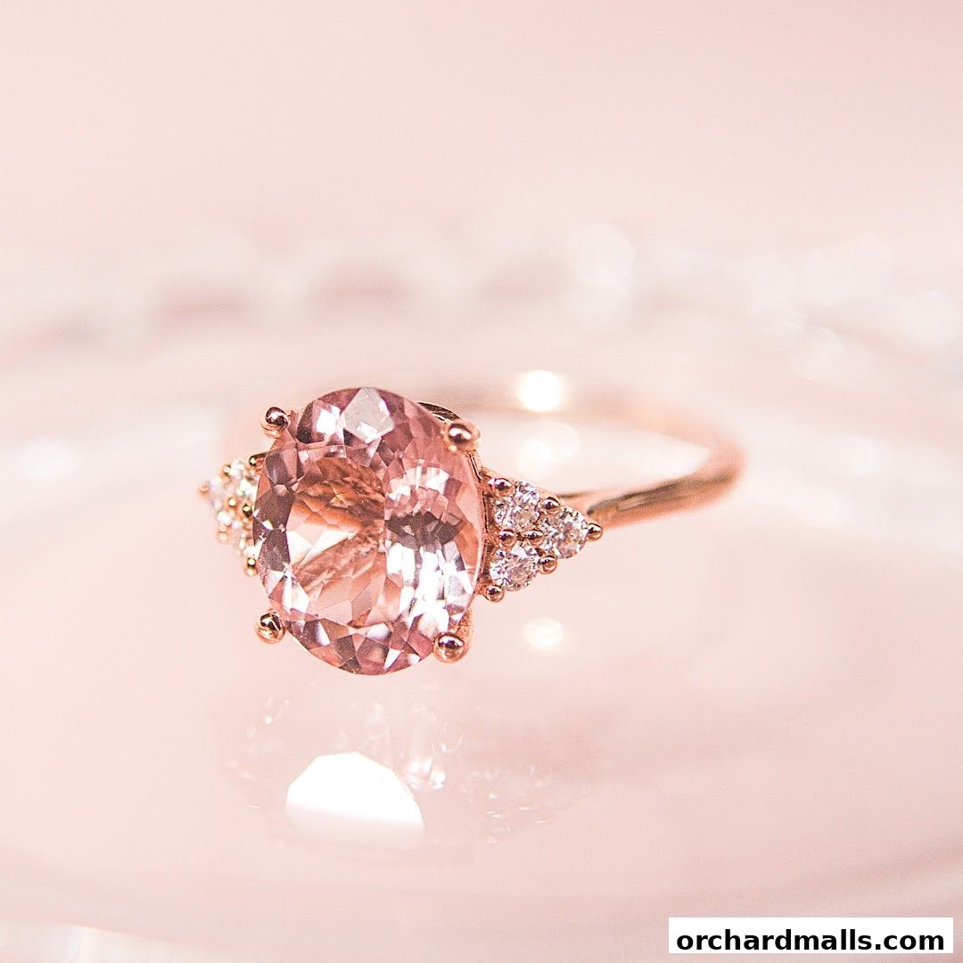A close-up shot of a rose gold ring with a large oval pink gemstone and smaller diamonds.