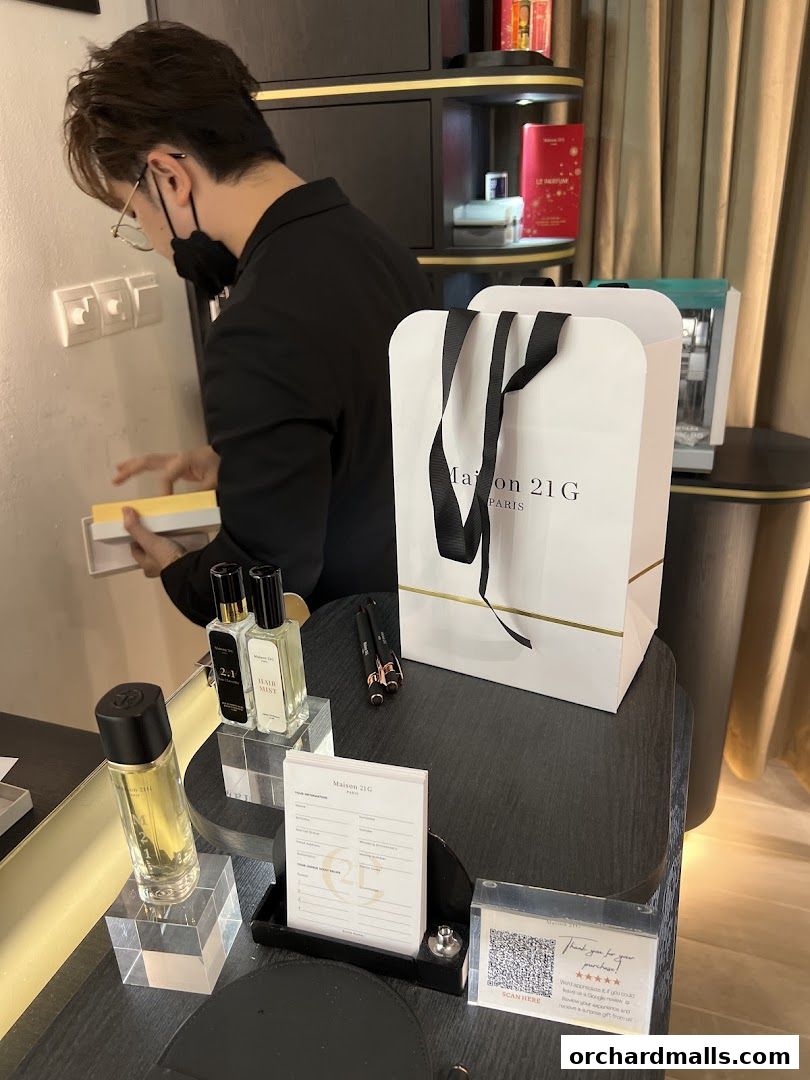 A person in a black jacket is arranging products in a perfume shop.