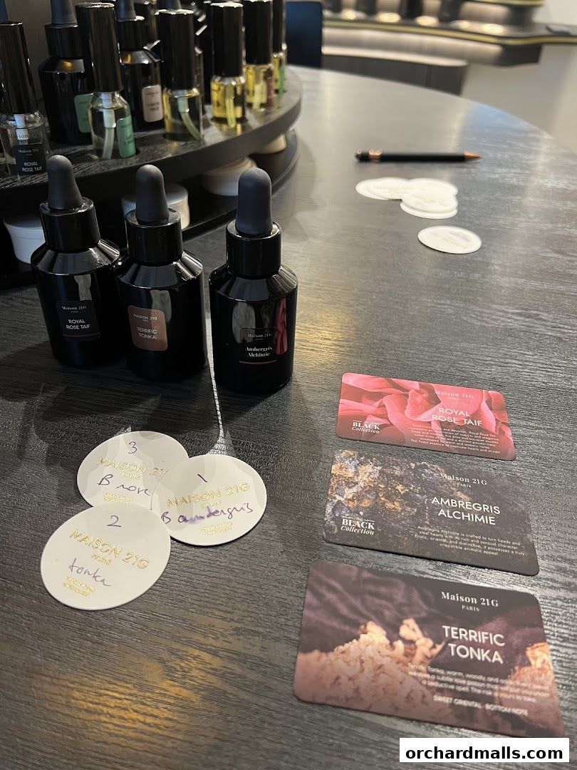 A display of Maison 21G perfumes with sample cards and bottles on a dark table.