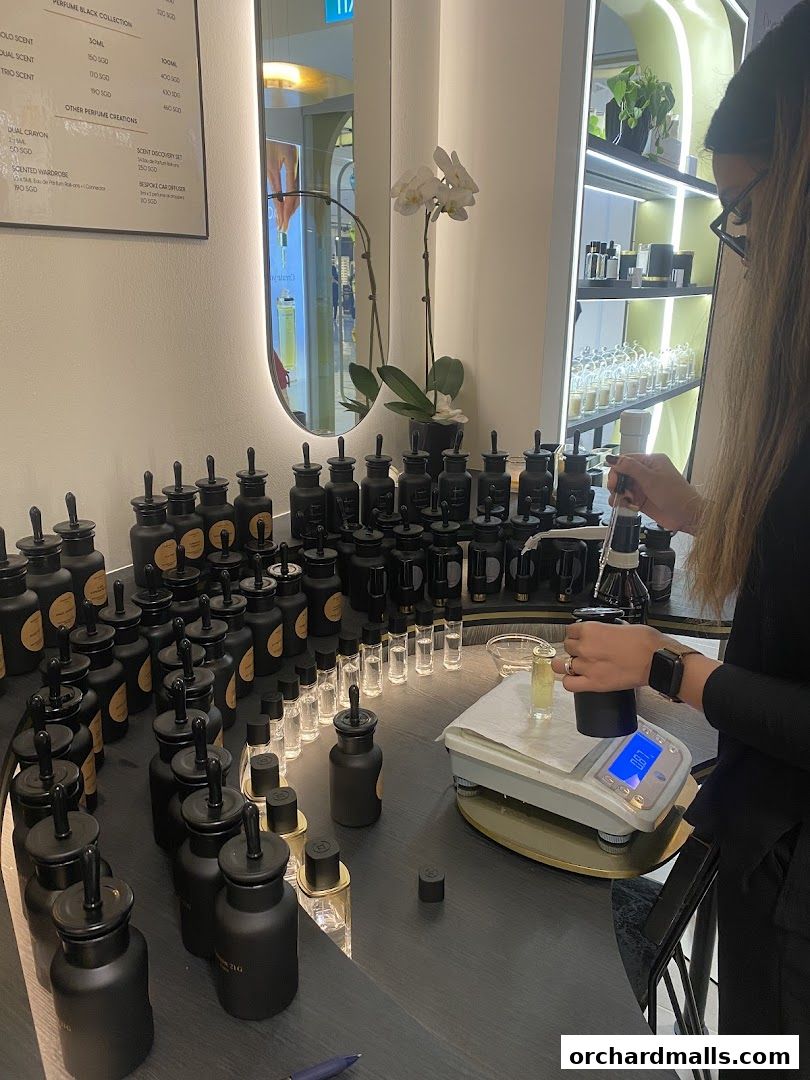 A person is creating a custom perfume with various bottles and equipment.