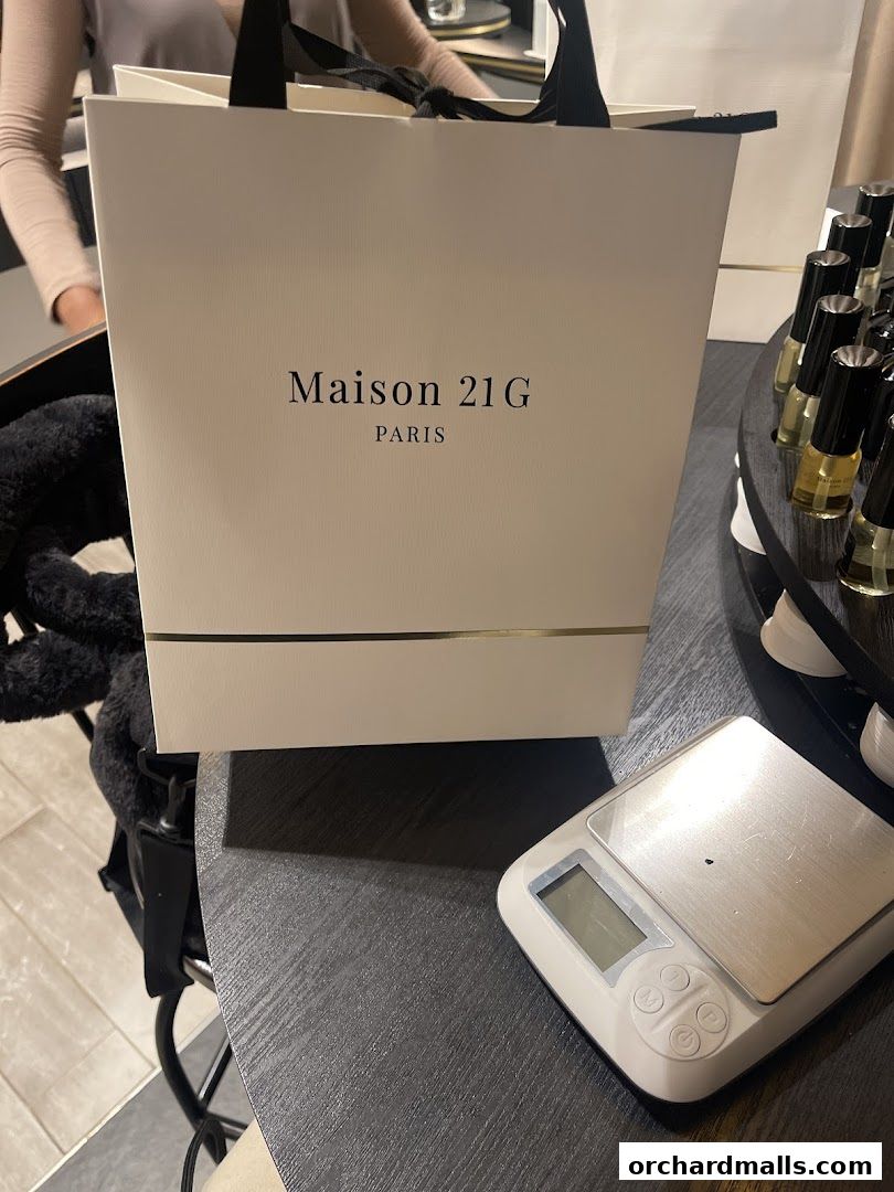 A white shopping bag with 'Maison 21G PARIS' logo and a digital scale.