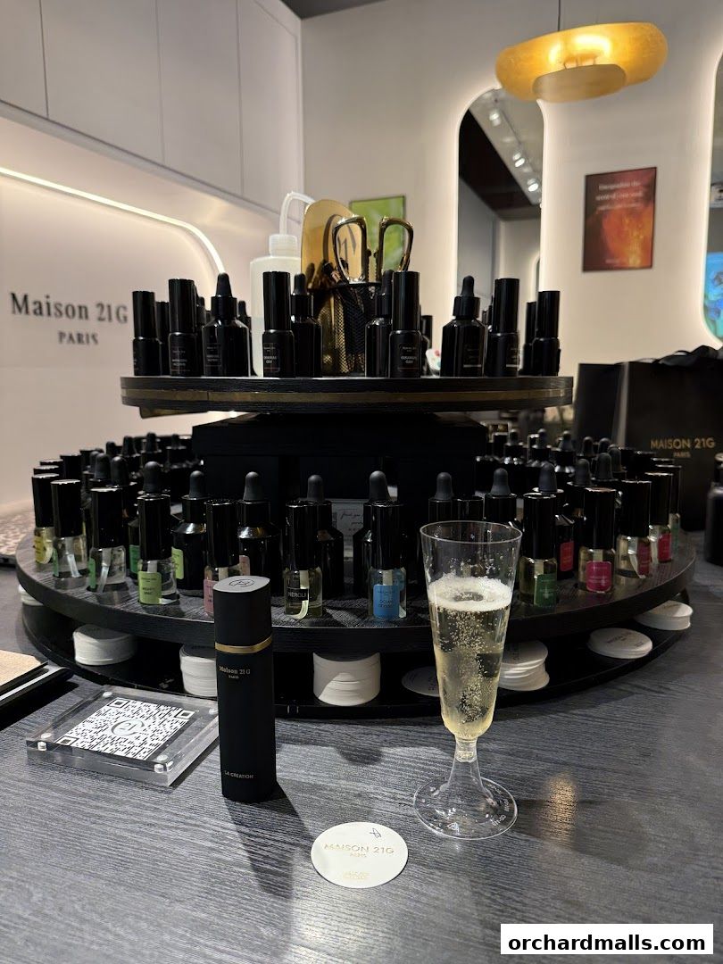 Maison 21G bespoke fragrance display with perfume bottles and a glass of champagne.