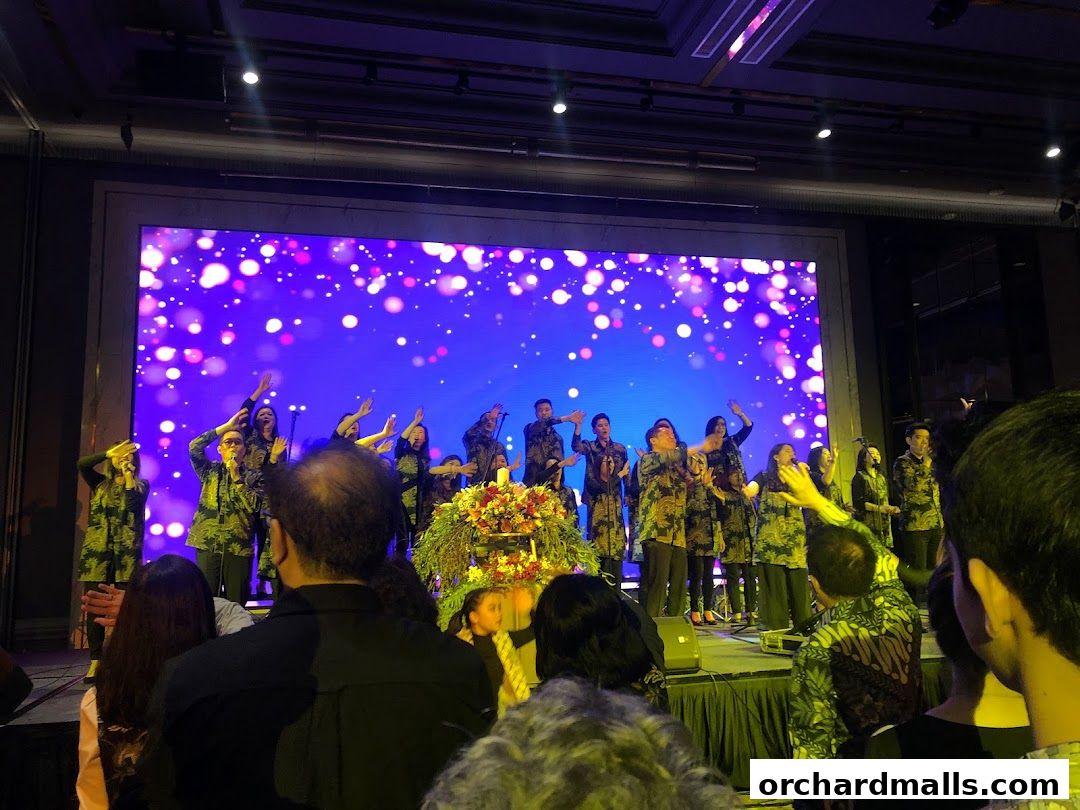A choir performs on stage with a large LED screen displaying colorful bokeh lights.