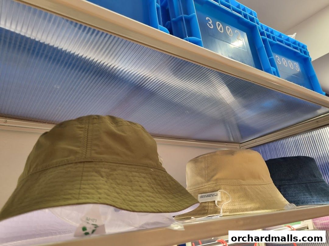 Three bucket hats in different colors displayed on a shelf with blue storage bins above.
