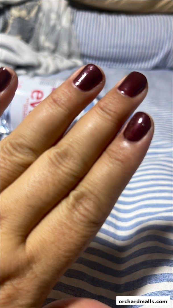 A close-up of a hand with freshly painted dark red nails.