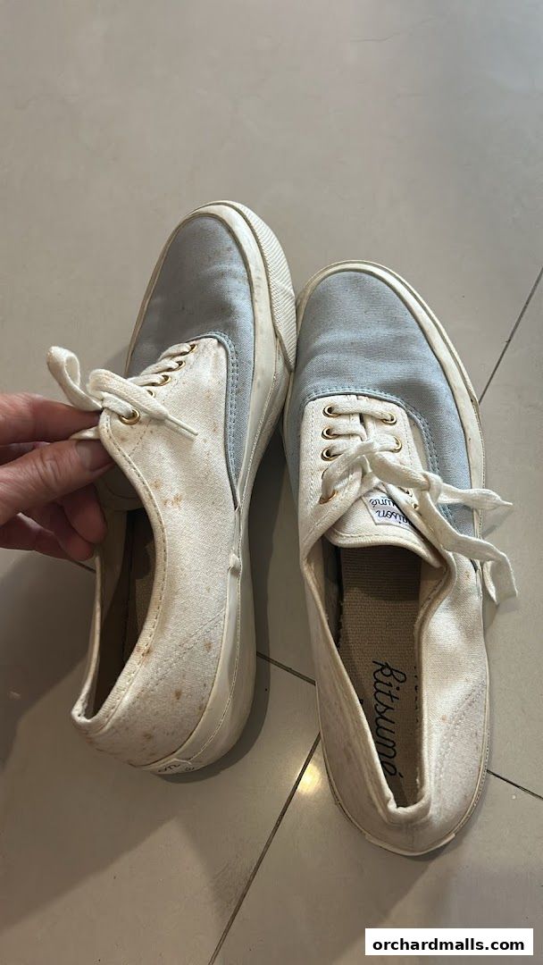 A pair of light blue and white canvas sneakers with laces and visible stains.