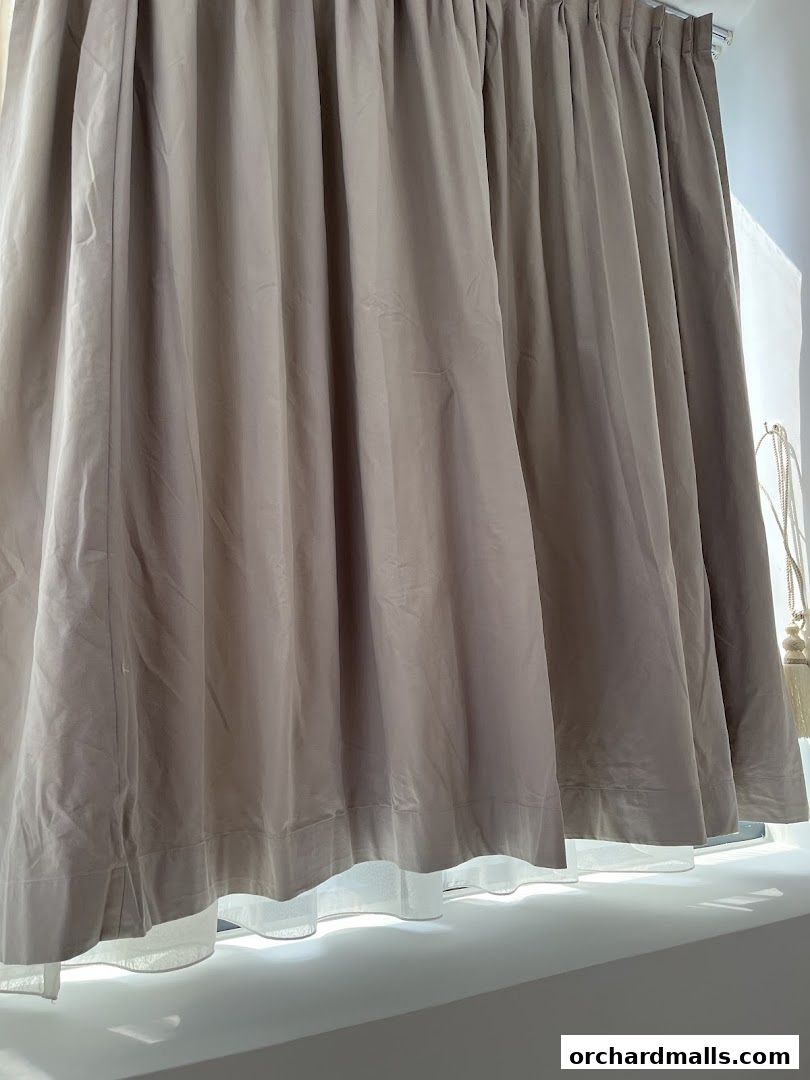 A close-up shot of beige curtains with a white sheer layer underneath.