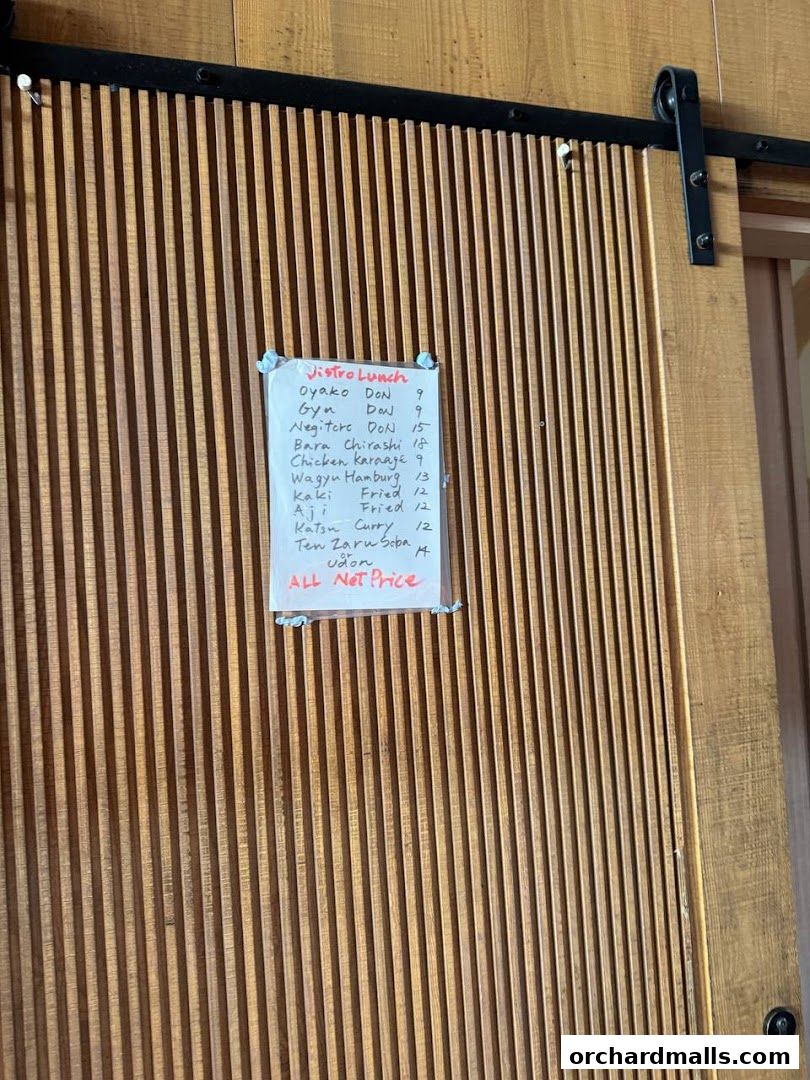 A handwritten lunch menu for Bistro Du Le Pin is displayed on a wooden slatted door.