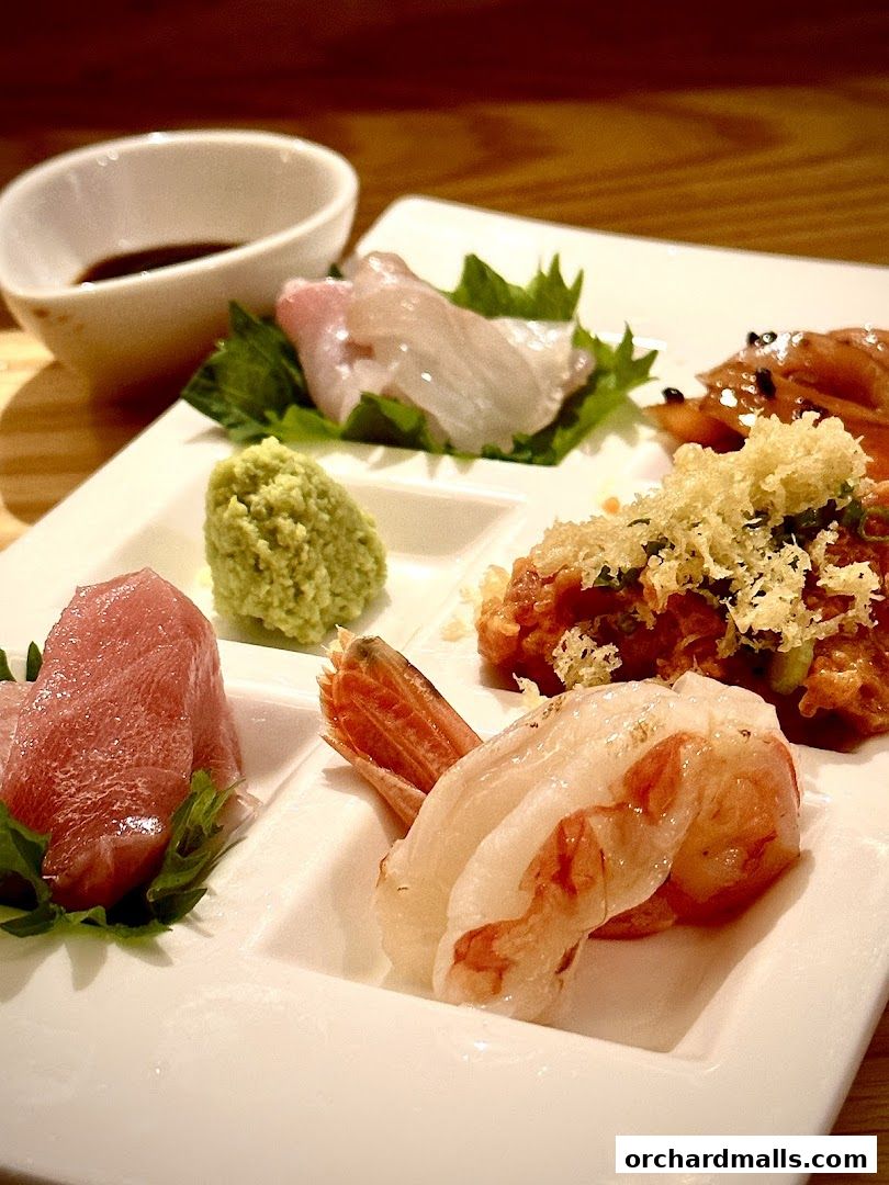 A platter of fresh sashimi and shrimp with wasabi and soy sauce.