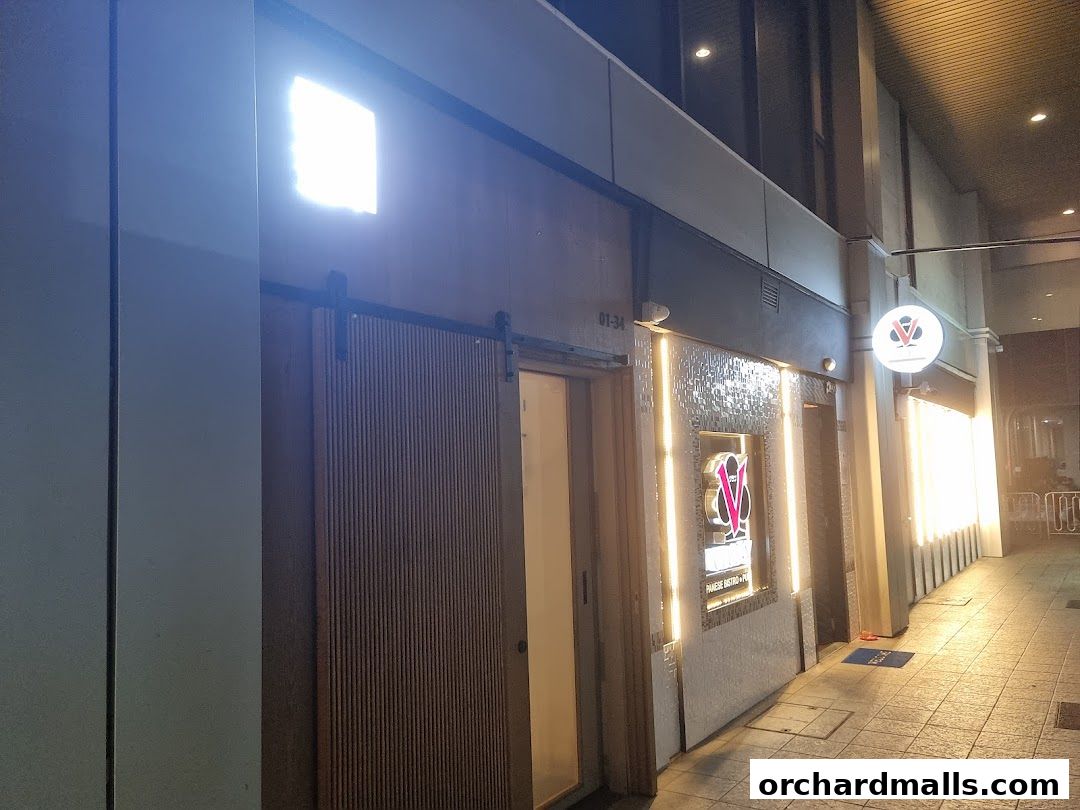 Exterior of Bistro Du Le Pin with illuminated signage and a sliding wooden door.