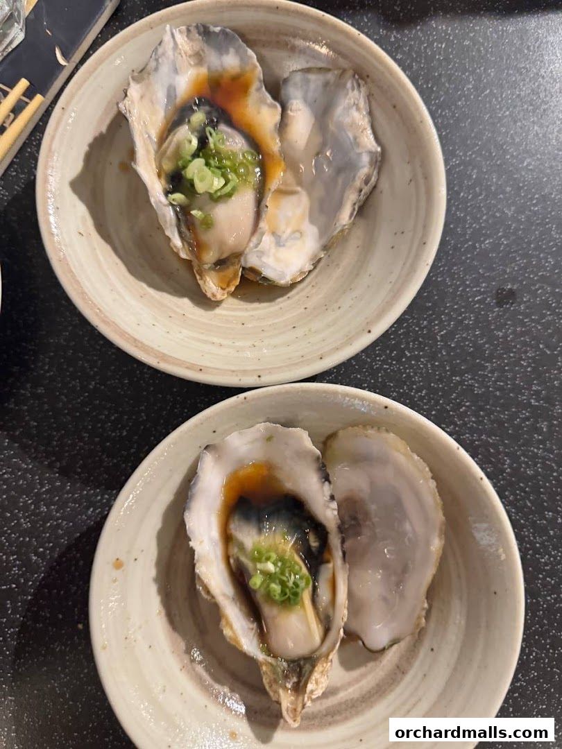 Two bowls of oysters served with sauce and green onions.