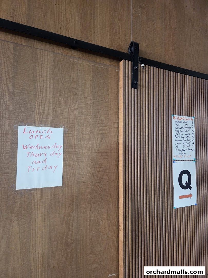 A wooden door with two handwritten signs indicating lunch hours and menu items.