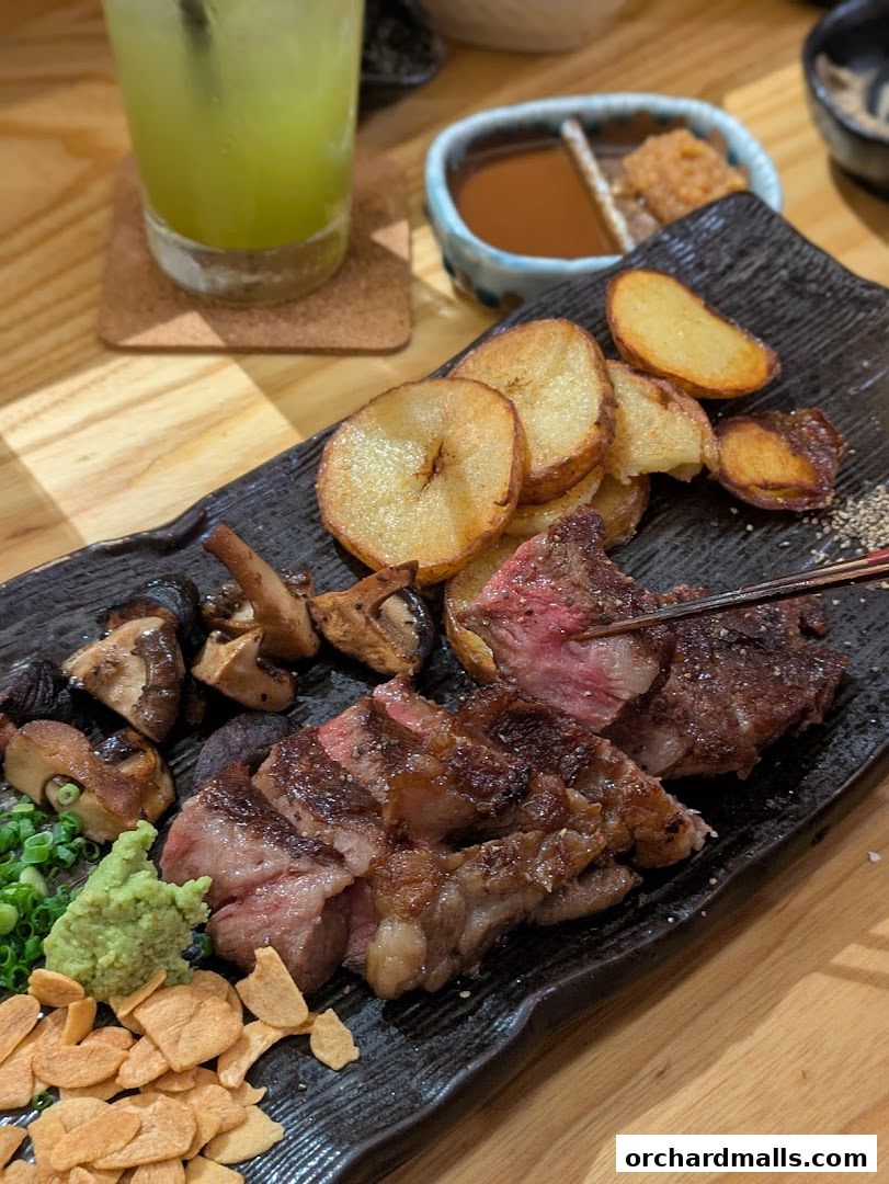 A delicious steak dish with roasted potatoes, mushrooms, and a side of wasabi and sauce.
