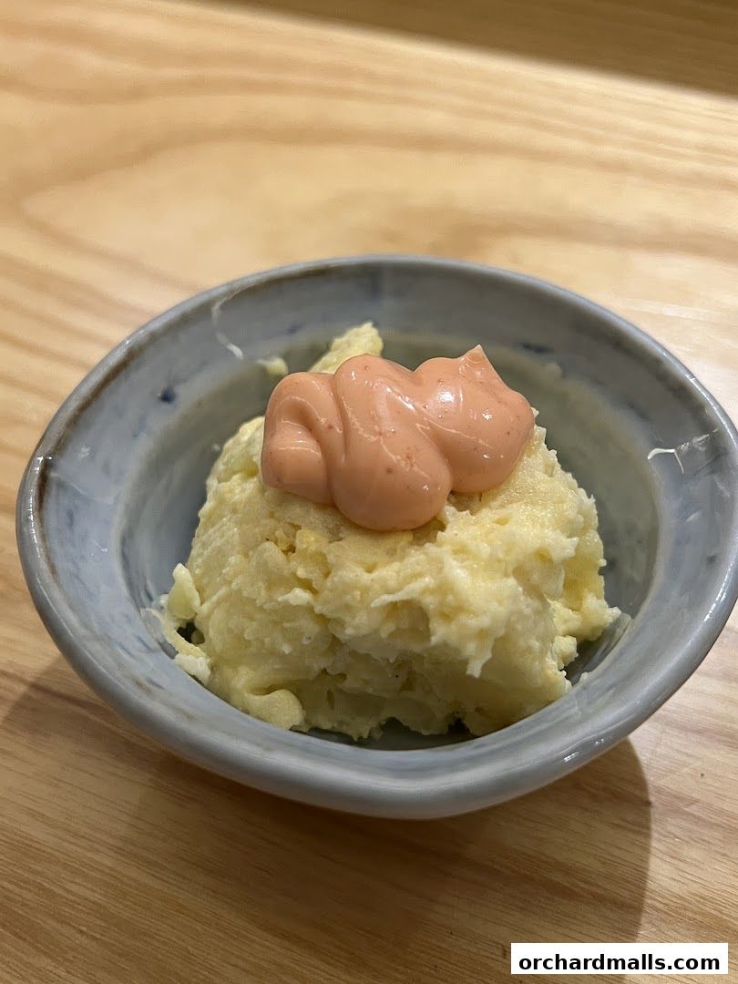 A close-up of a small bowl of mashed potatoes topped with a dollop of pink sauce.