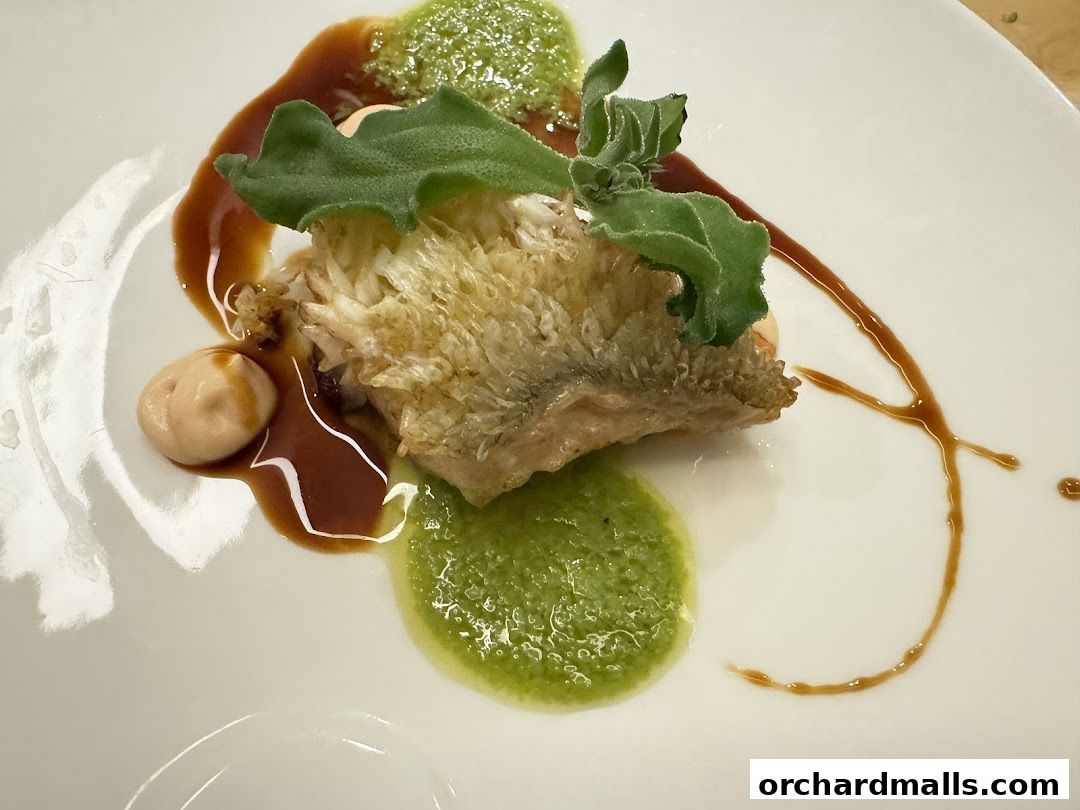 A beautifully plated dish with crispy fish, green puree, and sauce.
