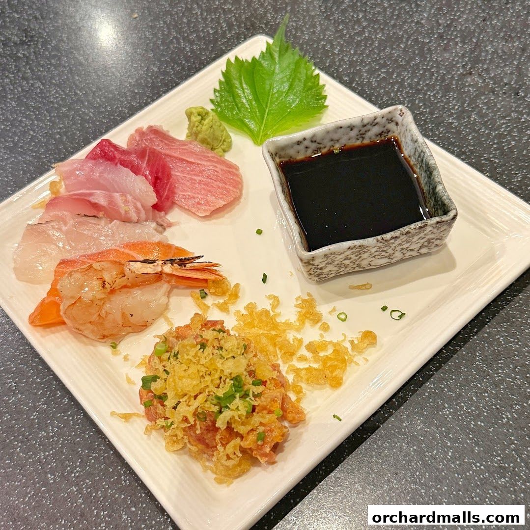 A plate of assorted sashimi, shrimp, and a tartare dish with soy sauce and wasabi.