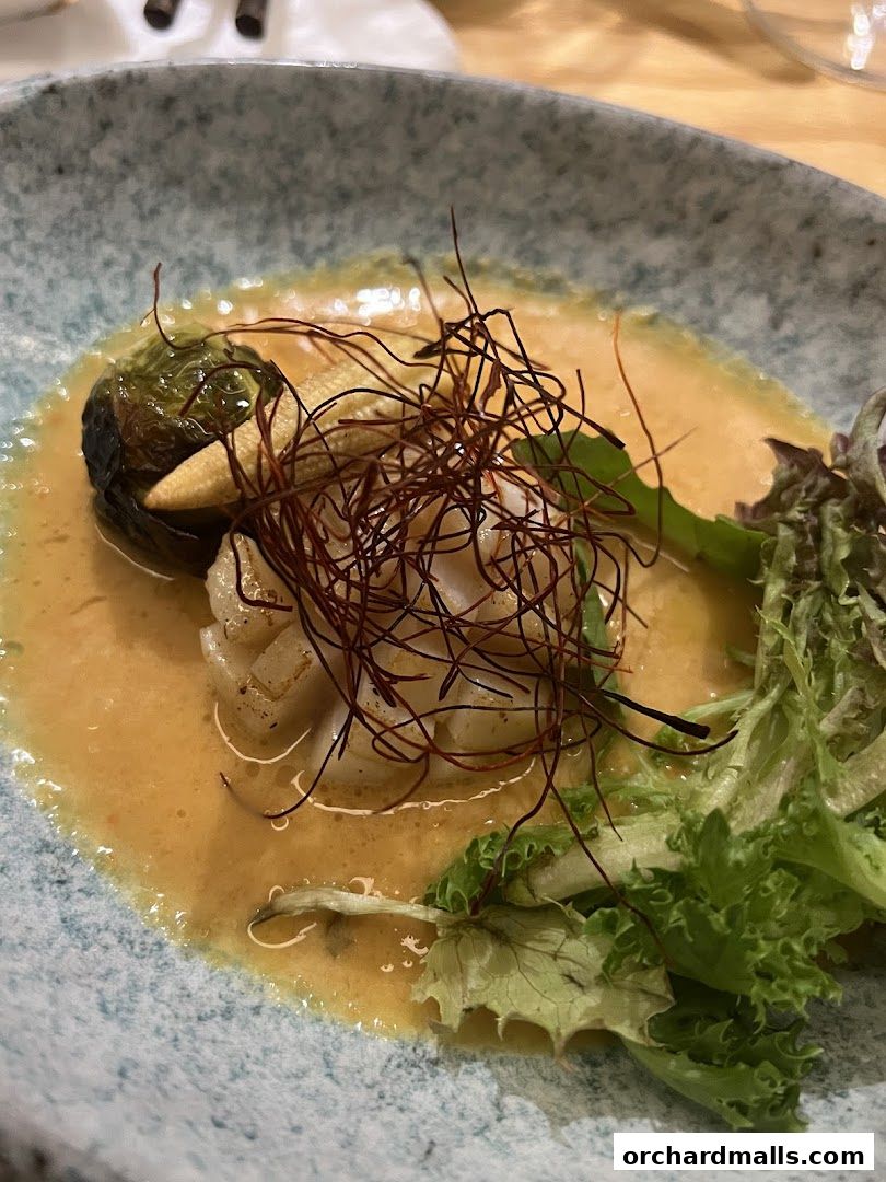 A beautifully plated dish with seafood, vegetables, and a rich sauce.