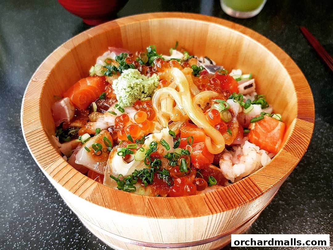 A close-up of a wooden bowl filled with a colorful assortment of fresh seafood and rice.