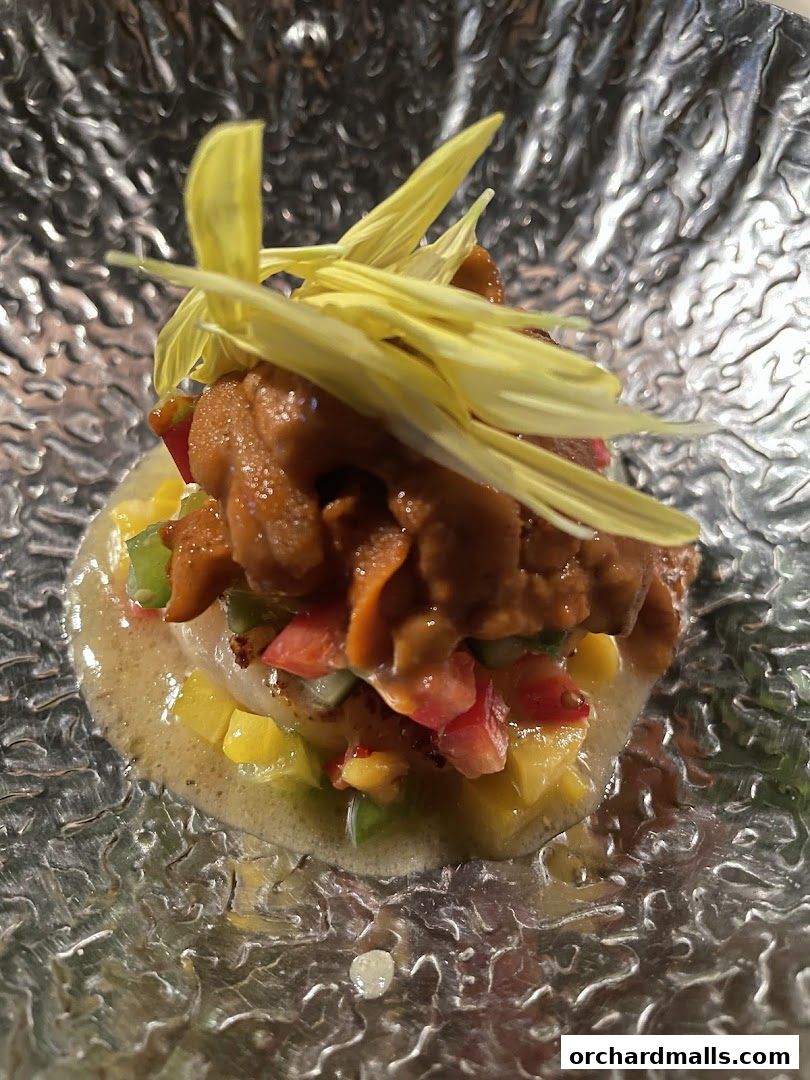 A close-up of a gourmet dish with seafood, vegetables, and edible flowers.