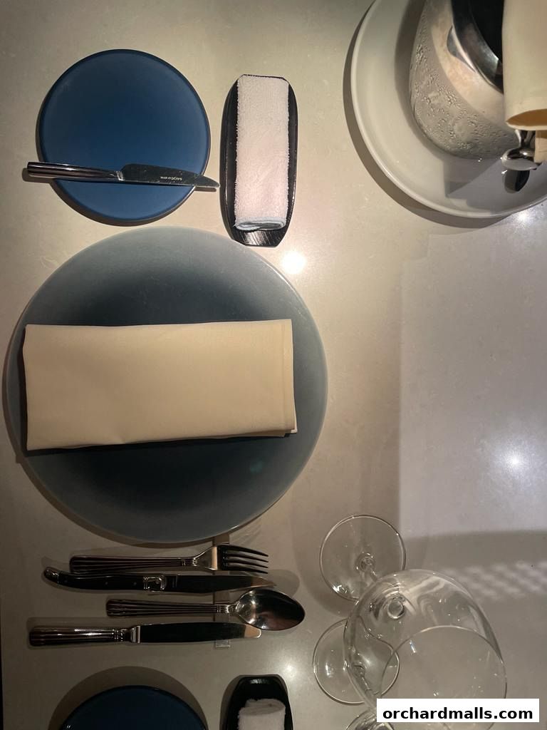 A table setting with plates, cutlery, napkins, and wine glasses.