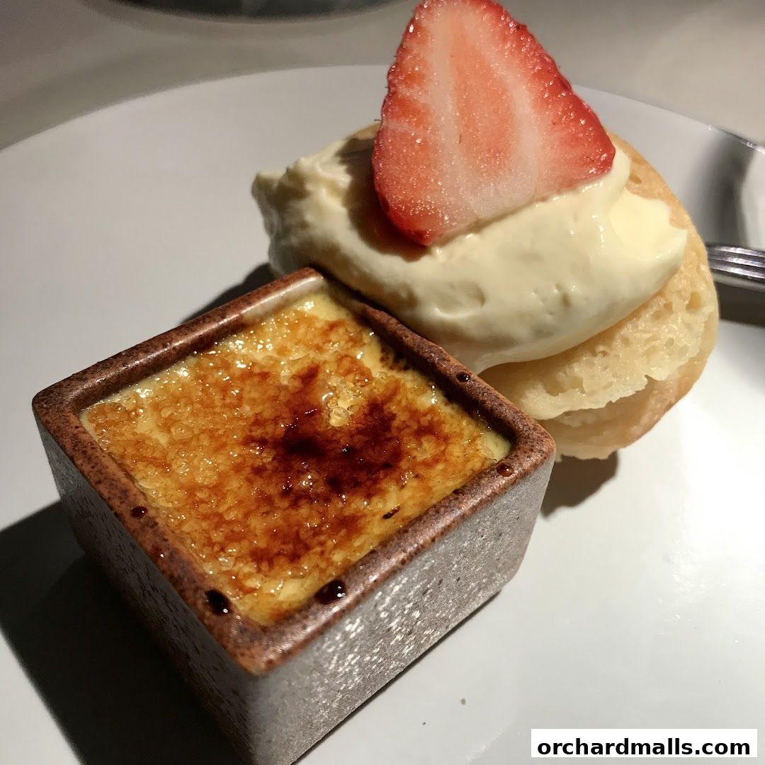 A close-up of a crème brûlée and a pastry with cream and strawberry.