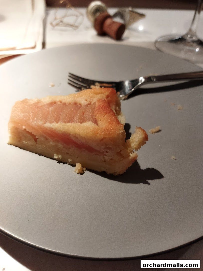 A slice of cake with fruit filling on a gray plate with a fork.
