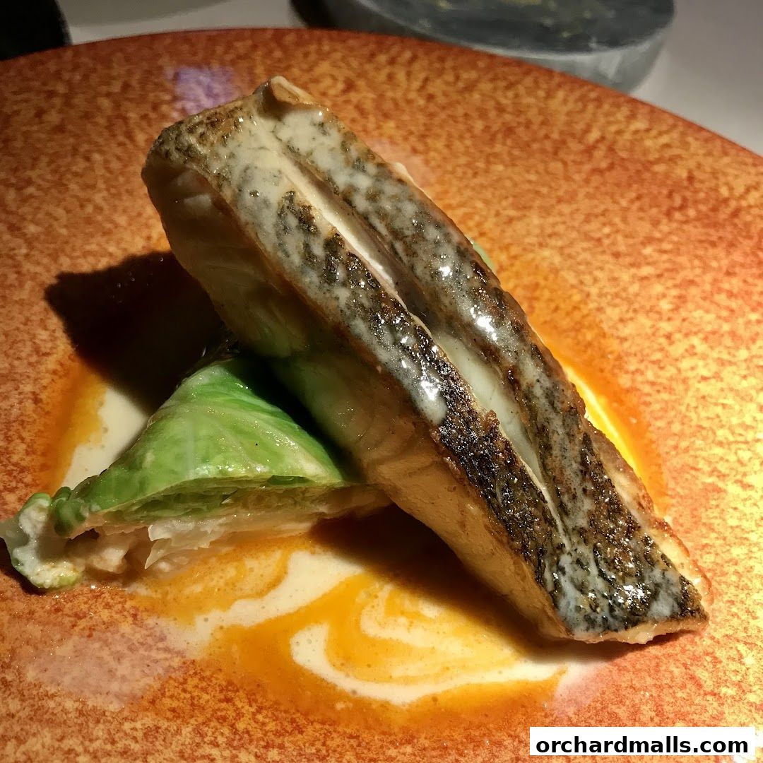 A close-up of a perfectly cooked fish fillet served with a side of cabbage on an artistic plate.